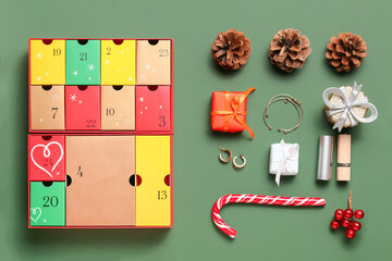 Advent calendar with Christmas decor, candy cane and jewelry on green background