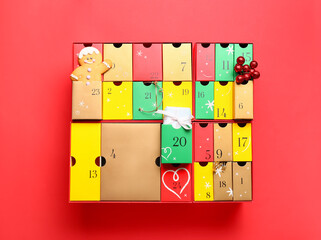 Winter advent calendar with jewelry, gift and cookie on red background