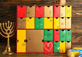 Advent calendar with dreidels and menorah for Hanukkah on dark wooden background
