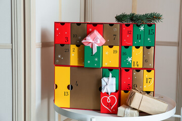 Advent calendar with Christmas gifts on table near folding screen
