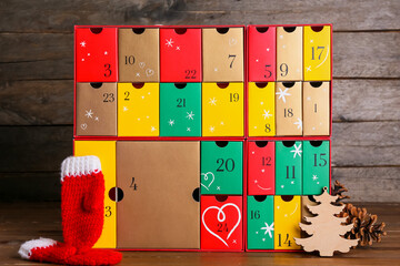 Advent calendar with gloves and fir cones on dark wooden background