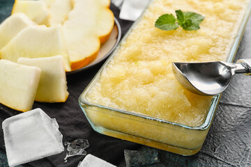 Bowl of tasty melon sorbet with scoop and mint on dark background