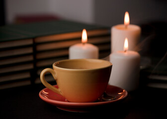 cup of coffee with hot smoke and three burning candles. on the desk at home, power outage (focus on...