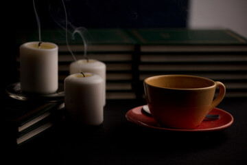 cup of coffee with unlit candles on the desk at home, power outage (focus on cup).