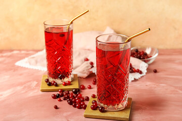 Glasses with tasty cranberry juice on color background