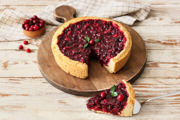 Board with tasty lingonberry pie on light wooden background