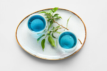 Plate with glasses of blue tea on white background