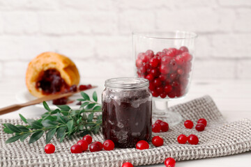 Jar with tasty lingonberry jam and fresh berries on table