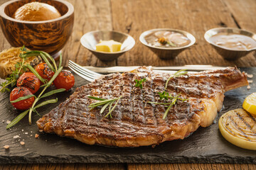 beef tomahawk steak on stone plate with sauce and bread and butter