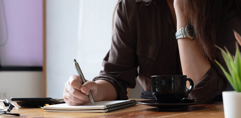 Cropped photo hand of woman writing making list taking notes in notepad working or learning online