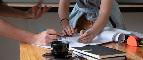Concept architects, engineer holding pen pointing equipment architects On the desk with a blueprint in the office.