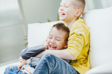 Two happy young brothers romping on a sofa together