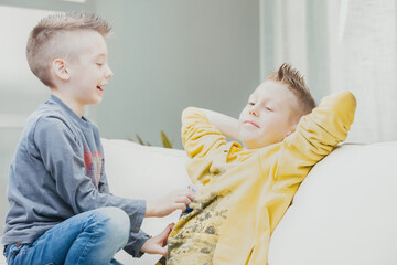 Mischievous young boy tickling his older brother - obrazy, fototapety, plakaty