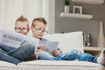 Two young boys wearing spectacles relaxing on a sofa