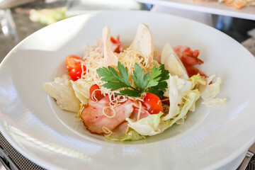 Egg, croutons, tomato, ham salad in a white plate on a table. High quality photo