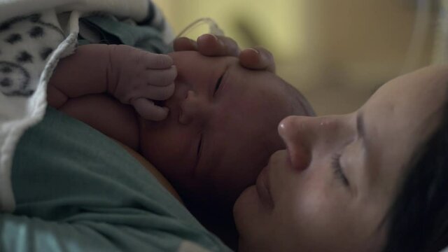 Portrait Of Mother And Newborn Baby, Mother Kisses Baby's Head, Motherhood Concept