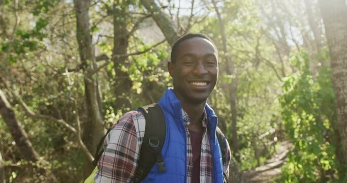 Portrait of smiling african american man in forest during hiking in countryside