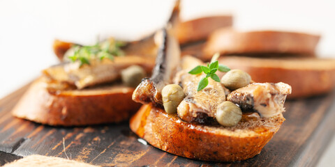 Sandwich - smorrebrod with sprats and capers on wooden board. Danish cuisine.