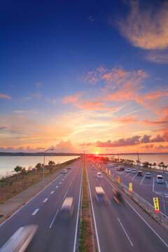 ロードパークの歩道橋上から望む本島側の海中道路と夕日, うるま市,沖縄県
