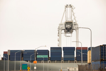 Port cranes offload cargo containers from sea vessels.