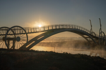 Bicycle-shaped bridge with water fog rising from the beach