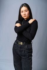 portrait of a girl in black clothes with long black hair on a gray background. Oriental beauty.