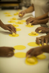 Human Hands making Raw and dry capeletti pasta on kitchen table