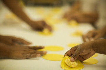 Human Hands making Raw and dry capeletti pasta on kitchen table