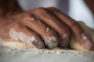 Human Hand making pasta - making Raw and dry pasta on kitchen table - flower