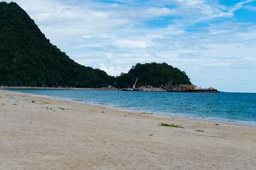 Beach at sea view with waves splashing or crash the sand with sunlight on sunny summer holiday with floating pier, island and blue sky background.