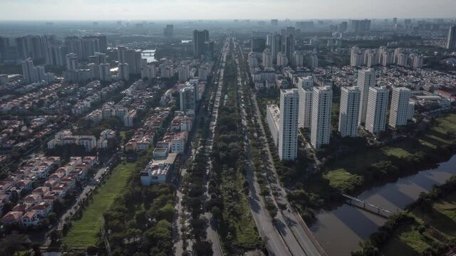 Drone hyperlapse along highway, ultra modern city with river, green space and high rise buildings seen from the air on a sunny day.
