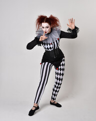   halloween, character, costume, figure pose, posing, portrait, gesture,  isolated,  magical, dynamic movement,  isolated,  studio background,  red hair, circus, theatre, jester, clown,  
full length,