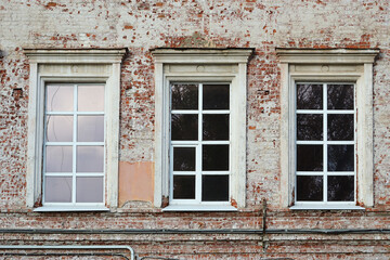 New windows on an old beige and red tattered brick wall