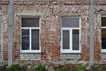 Fototapeta na wymiar New windows on an old beige and red tattered brick wall