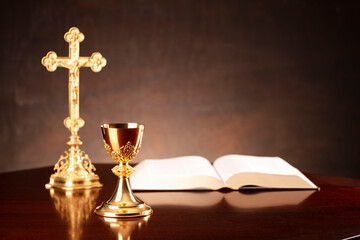All Saints day. Catholic religion concept. The Cross,  Holy Bible and golden chalice on the altar. 