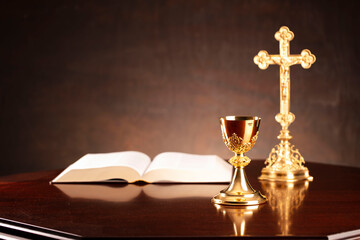 All Saints day. Catholic religion concept. The Cross, Holy Bible and golden chalice on the altar.