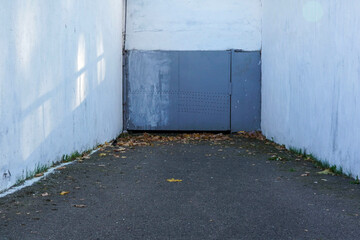 Fototapeta premium Photo of gray metal doors to the garage and white walls on the street