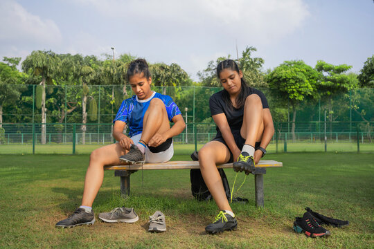 Two young athlete girls wearing their sports shoes on the field