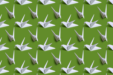 Seamless background with paper cranes. White paper birds on a plain background. Crafts from paper with children. Classic origami.