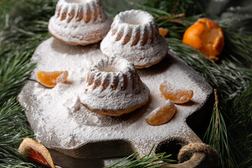 Muffins sprinkled with powdered sugar are on a wooden board. New Year's composition.