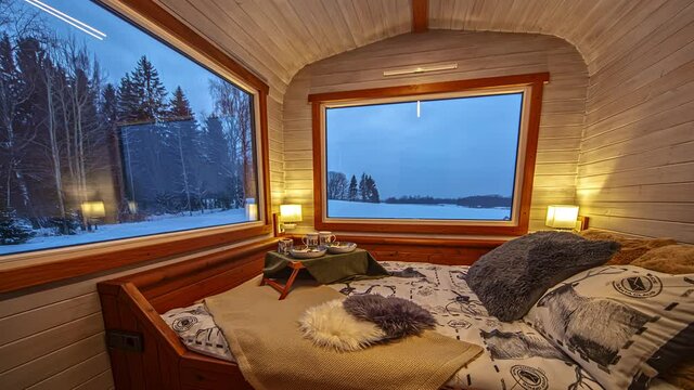 Time lapse shot of cozy decorated tiny house with bed and beautiful winter nature view through windows