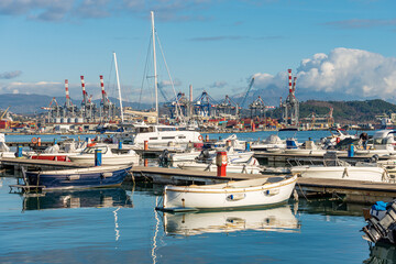 Fototapeta premium Large port with many boats moored, cranes and container ships. International harbor in the Gulf of La Spezia on a sunny winter day. Liguria, Italy, Europe.