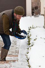 Man with beard sculpts  snowball in yard