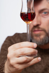 Glass with grappa in man hand close up