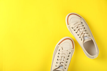 Pair of beige sneakers on yellow background