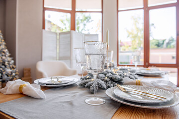 Festive New Year wooden table setting. Christmas tablecloth, white plates, gold cutler. Copy space