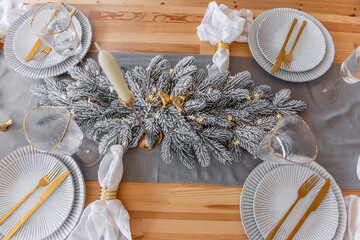 Festive New Years table setting top view, with white wavy plates, gold cutlery. Fashionable interior