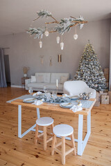 Stylish, trendy living room interior is festively decorated. Christmas tree under are gifts