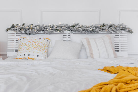 New Years interior. On the festive bed there is white bed linen with ornamented pillows mustard rug