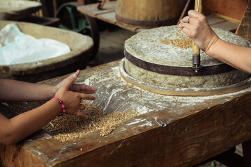 Hands of children making a flour using traditional flour grinder made ofd stone..